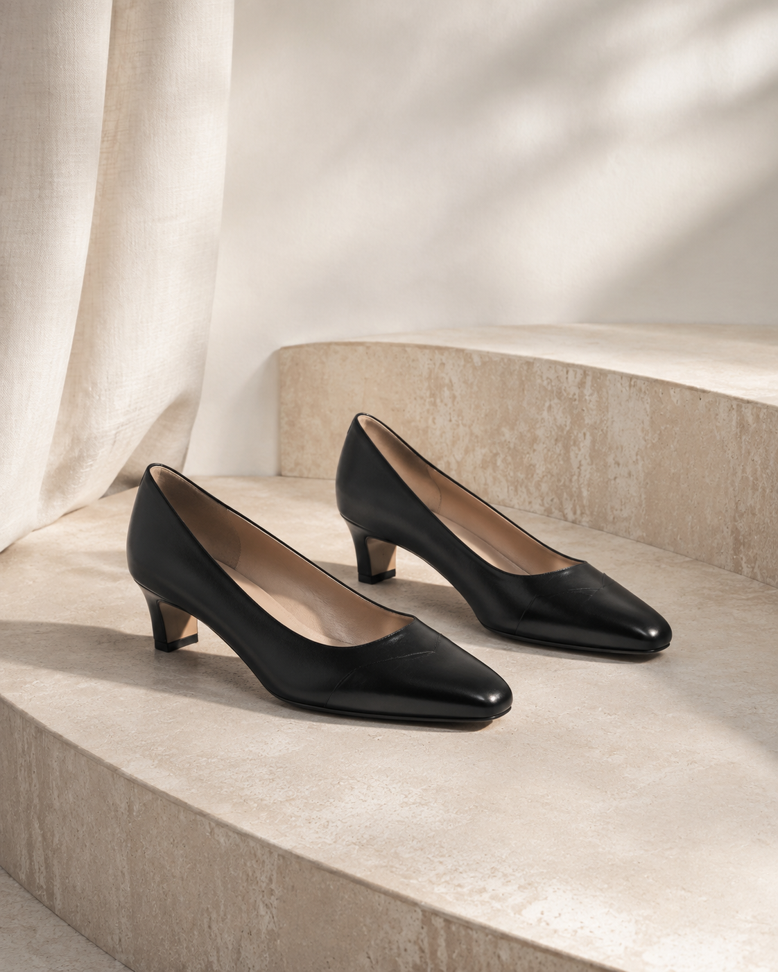 Unbranded black leather shoes in a warm ivory studio